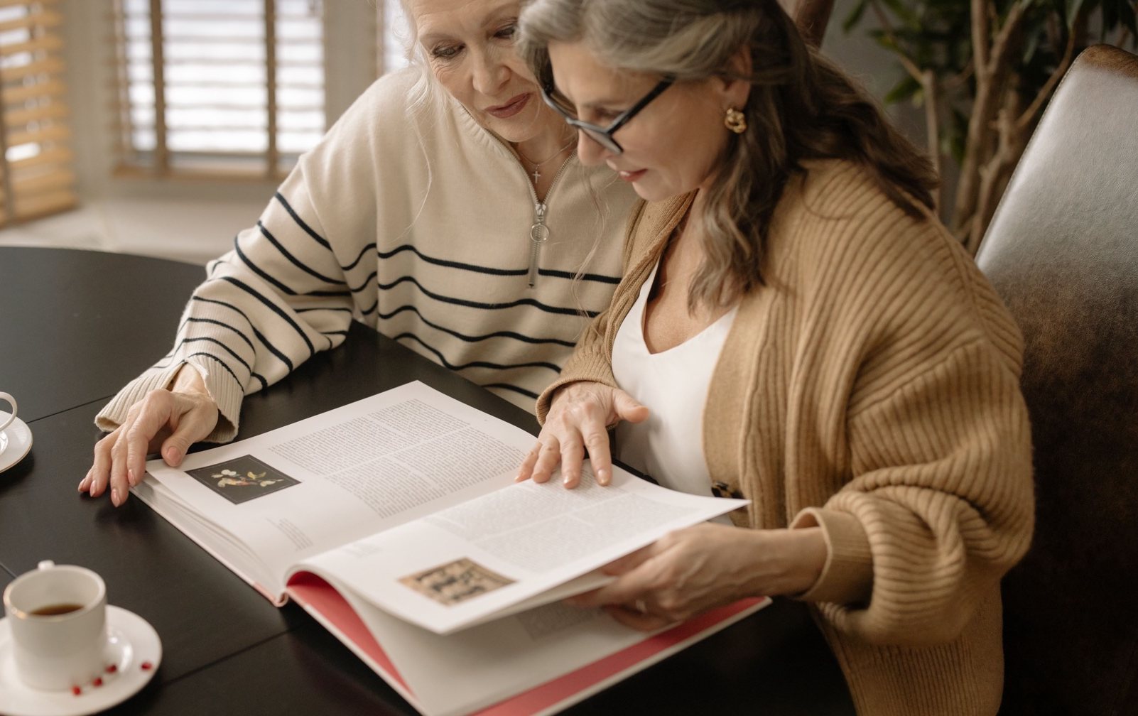 Two women sitting together at a table, looking through written material